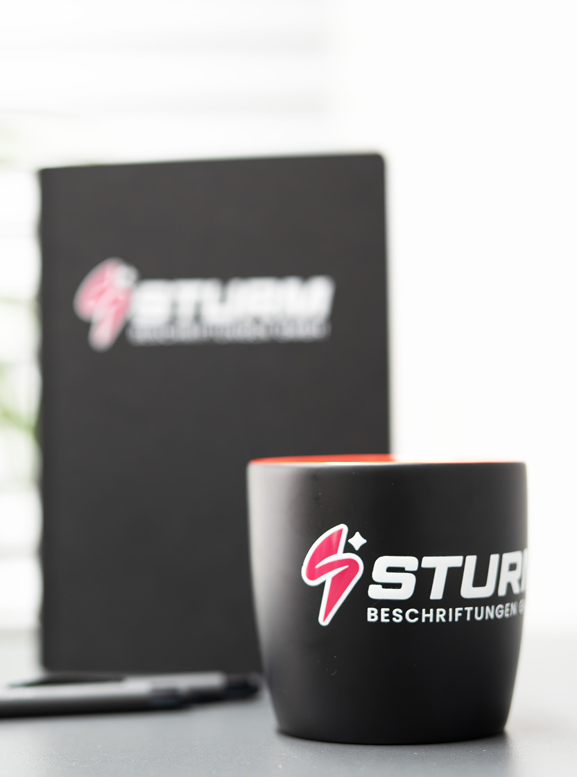 Eine Sturm Tasse, ein Buch und ein Stift.